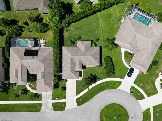 Aerial perspective of residential properties featuring concrete driveways, cul-de-sac positioning, screened-in swimming pools, and mature landscaping