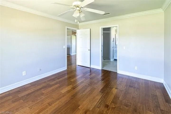 Interior space featuring wood-finish flooring, white crown molding, and a central ceiling fan with integrated lighting
