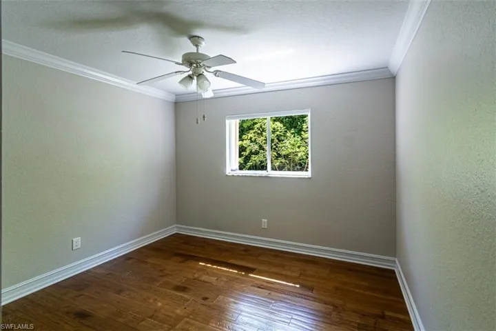 Wood-finish flooring, crown molding, and white-finish ceiling fan with integrated lighting