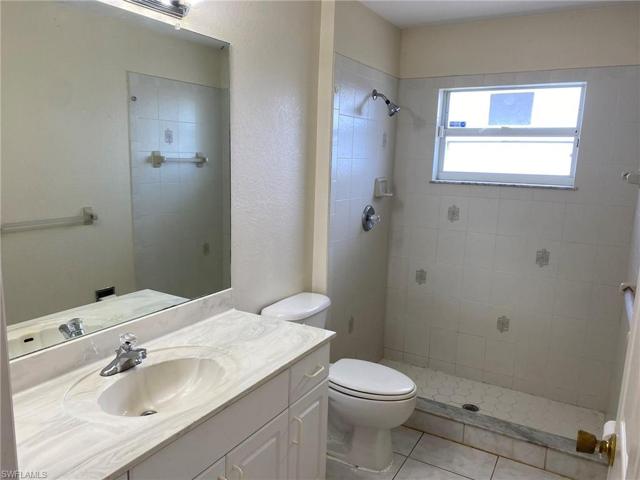 Guest bath has single vanity and tiled shower.