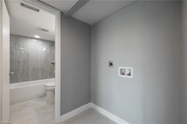 Washroom with hookup for a washing machine, light marble finish flooring, and electric dryer hookup