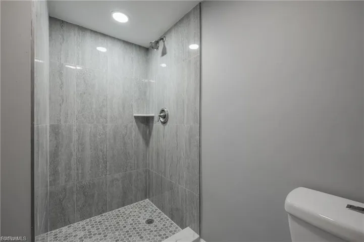 Full bathroom with tiled shower and recessed lighting