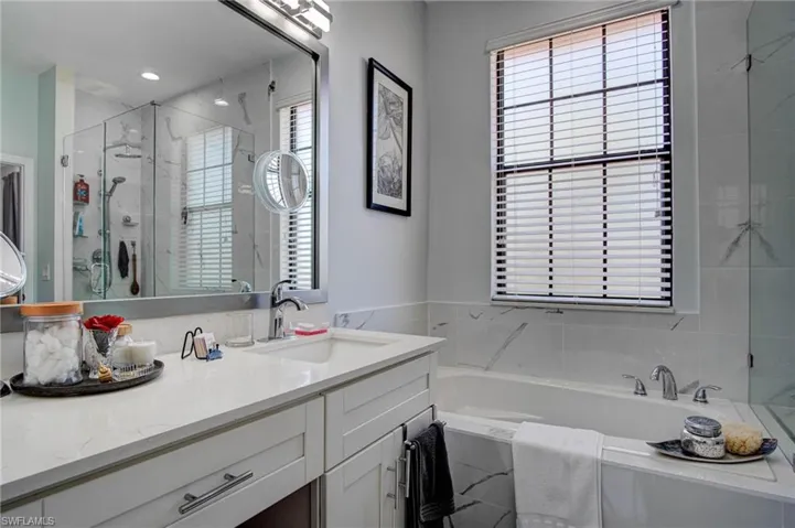 Bathroom featuring vanity with extensive cabinet space and shower with separate bathtub