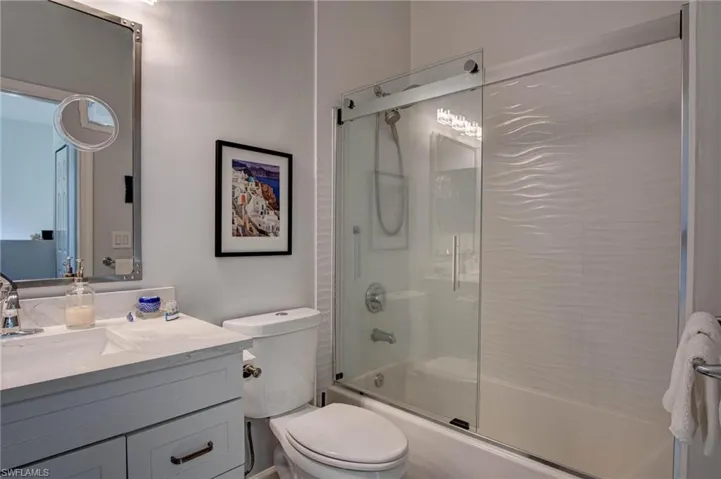 Full bathroom featuring combined bath / shower with glass door, vanity, and toilet