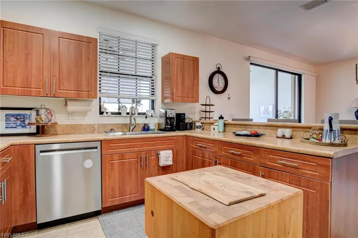 Kitchen with a center island, sink, stainless steel dishwasher, and light tile floors