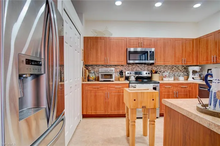 Kitchen featuring stainless steel appliances, backsplash, and light tile floors