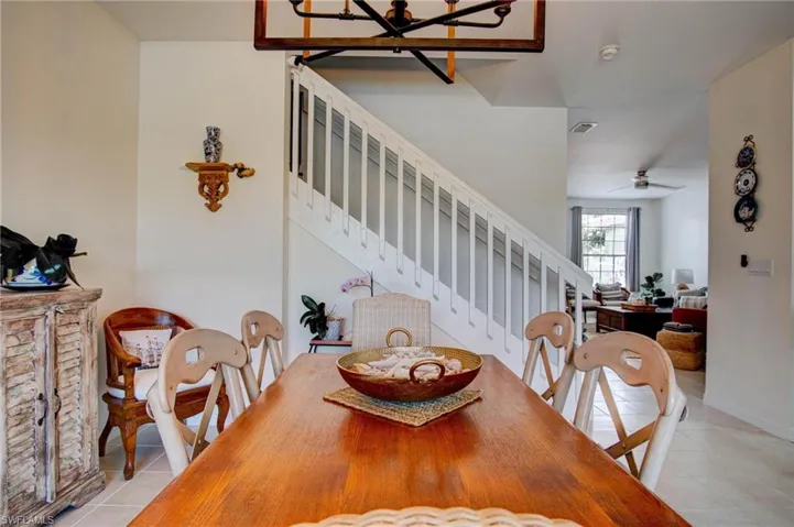 Tiled dining space featuring ceiling fan with notable chandelier