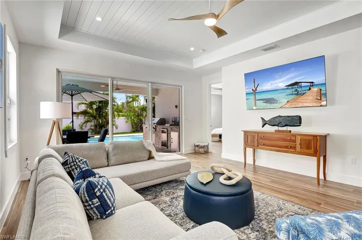 Living room featuring a raised ceiling, hardwood / wood-style floors, and ceiling fan