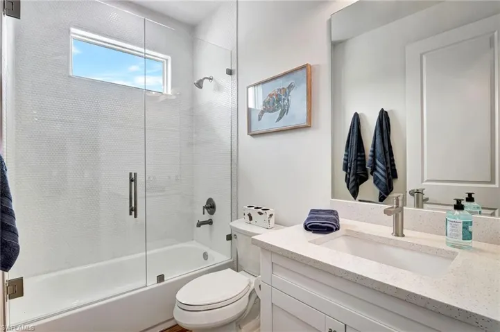 Full bathroom featuring vanity, enclosed tub / shower combo, and toilet