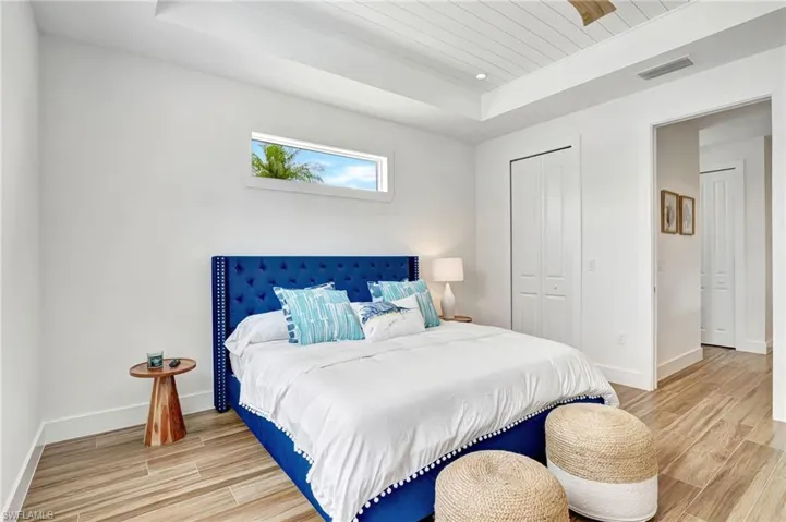 Bedroom featuring a closet, light wood-type flooring, and a tray ceiling