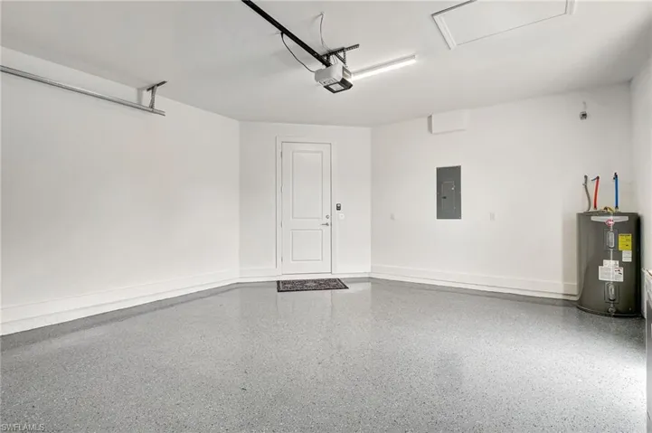 Garage featuring electric water heater, a garage door opener, and electric panel, and upgraded epoxy floors