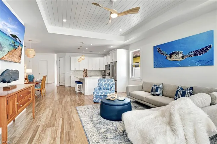 Living room featuring ceiling fan, light hardwood / wood-style floors, and a tray ceiling