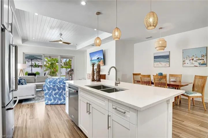 Kitchen featuring white cabinetry, pendant lighting, light wood-type flooring, sink, and a kitchen island with sink