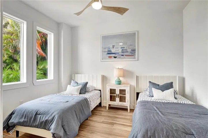 Bedroom with light hardwood / wood-style flooring, multiple windows, and ceiling fan