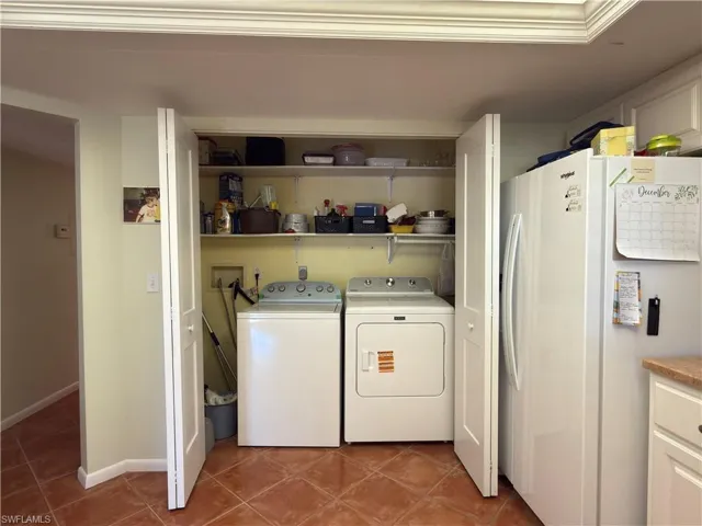 Laundry area with independent washer and dryer and dark tile patterned floors