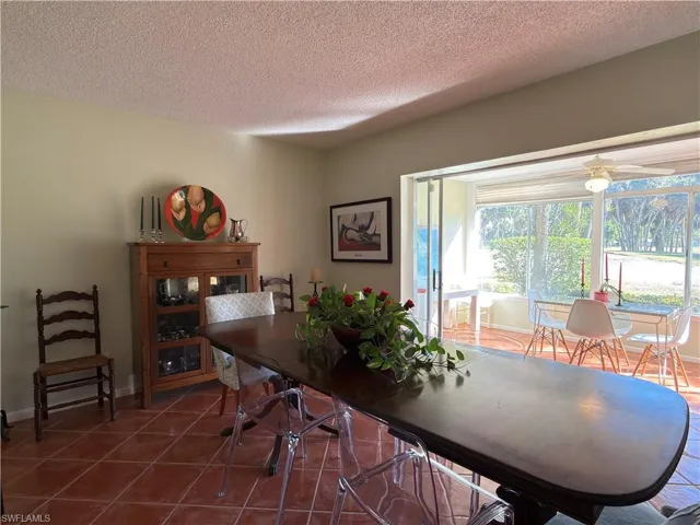 Dining area with a textured ceiling, tile patterned floors, and a ceiling fan