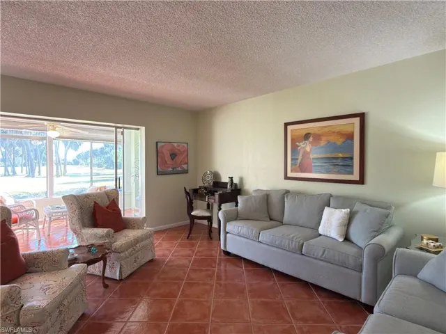 Tiled living room with a textured ceiling and baseboards