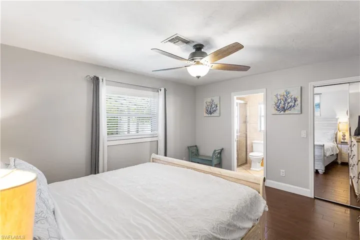 Bedroom with connected bathroom, dark wood-type flooring, a closet, and ceiling fan