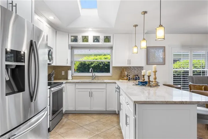 Kitchen with backsplash, appliances with stainless steel finishes, sink, and a healthy amount of sunlight