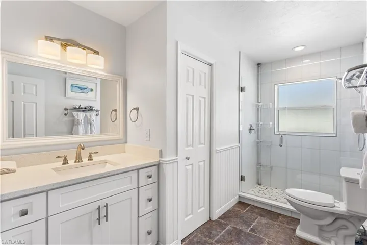 Bathroom featuring a shower with shower door, vanity with extensive cabinet space, tile flooring, and toilet