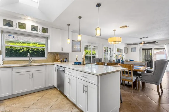 Kitchen featuring kitchen peninsula, pendant lighting, sink, tasteful backsplash, and light tile floors