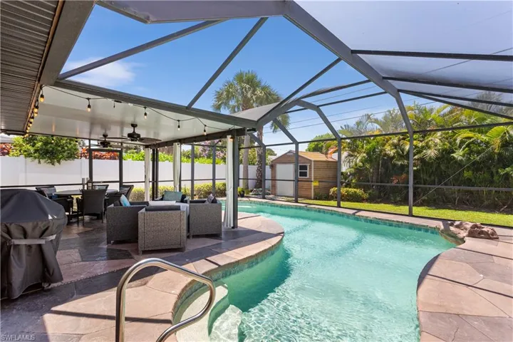 View of swimming pool with a patio, glass enclosure, and a storage unit