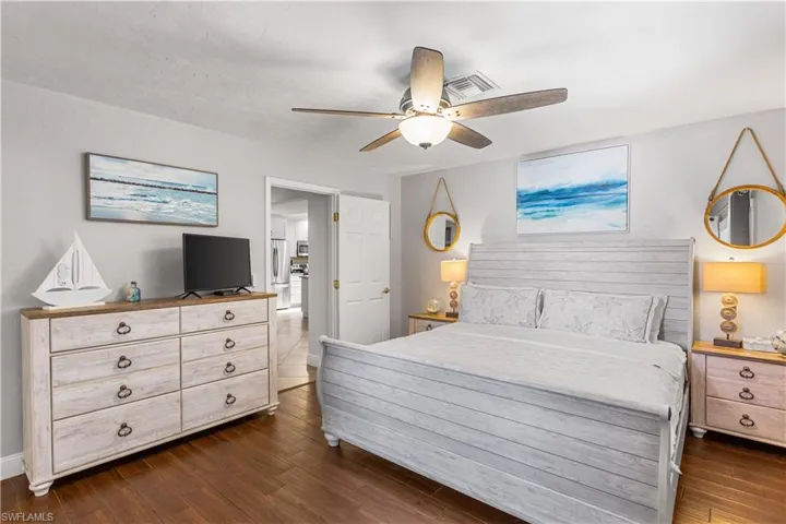Bedroom with ceiling fan, stainless steel fridge, and dark wood-type flooring