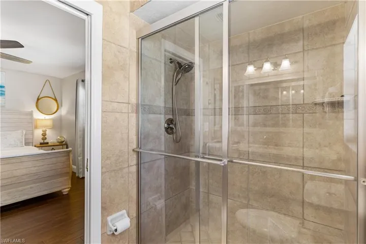 Bathroom with ceiling fan, vanity, hardwood / wood-style flooring, and a shower with door