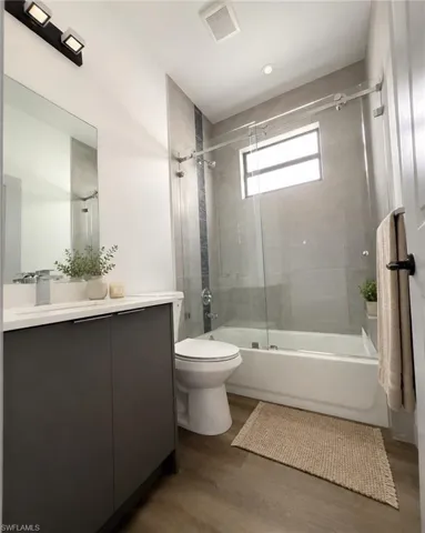 Modern bathroom featuring a dark grey vanity with white countertop, chrome faucet, and a large wall mirror