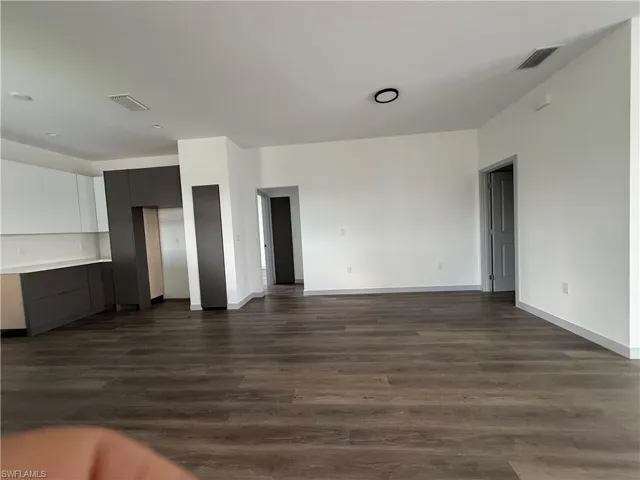 Open-concept living space featuring wood-finish flooring, white walls, and contemporary baseboards