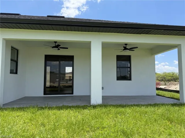 Expansive covered trussed in lanai featuring dual ceiling fans, a sliding glass door, and a large window