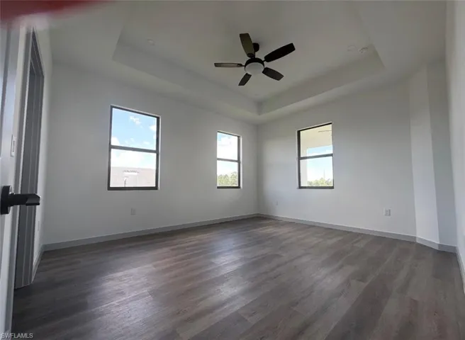 Spacious master bedroom w/space for sitting area featuring tray ceiling and a ceiling fan