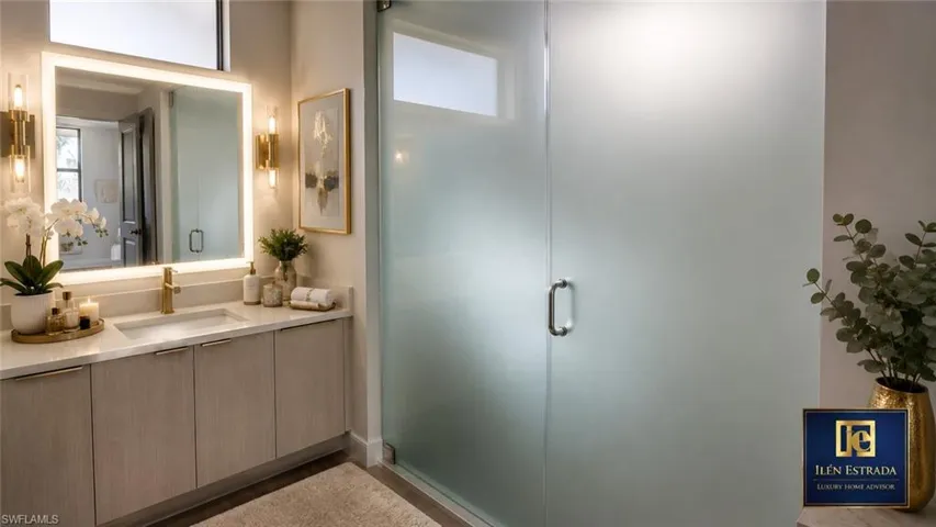 Contemporary bathroom featuring a single vanity with light wood-finish cabinetry, a white countertop, and a rectangular undermount sink with a gold-toned faucet