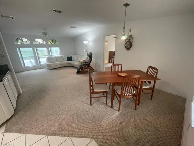 Dining space featuring vaulted ceiling, light carpet, and a ceiling fan