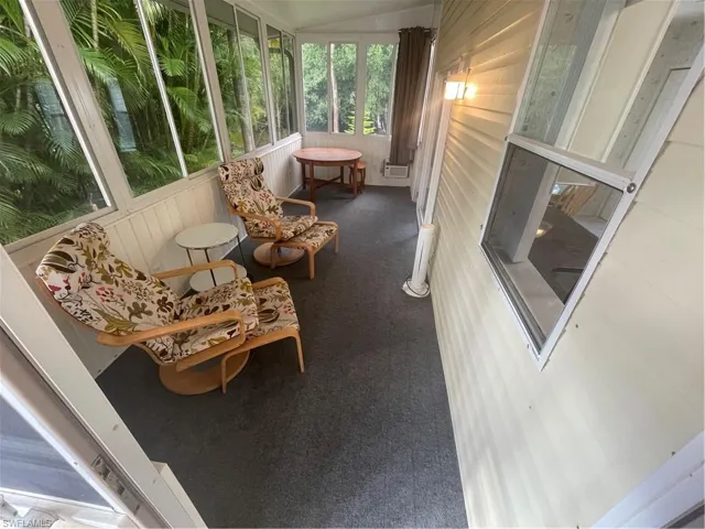 Sunroom / solarium featuring carpet, wood walls, and lofted ceiling