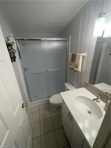 Full bath with a stall shower, vanity, and light tile patterned floors