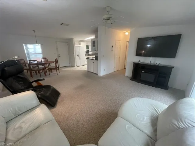 Living room featuring light colored carpet and a ceiling fan