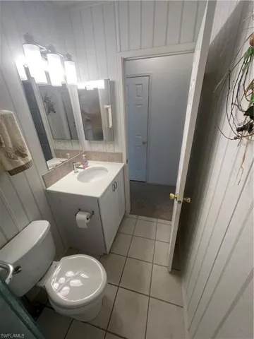 Half bath featuring vanity, light tile patterned floors, and wooden walls