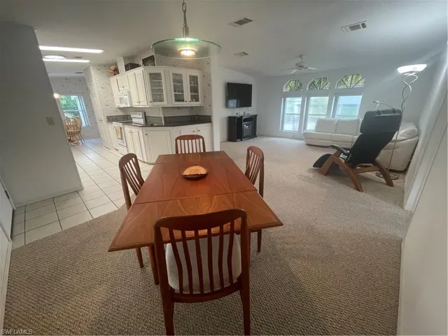 Dining room featuring light colored carpet, plenty of natural light, light tile patterned floors, and a ceiling fan
