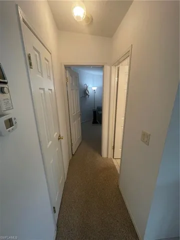 Hallway featuring light colored carpet and baseboards