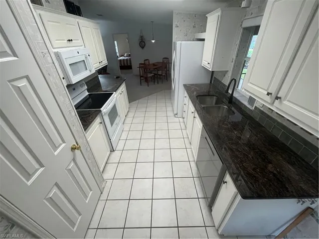 Kitchen featuring white cabinetry, range, light tile patterned floors, decorative backsplash, and dishwasher