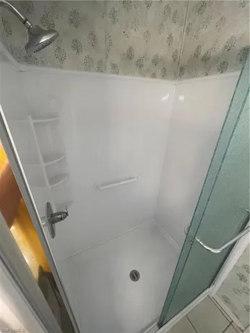 Full bathroom featuring a stall shower, tile patterned floors, and wallpapered walls