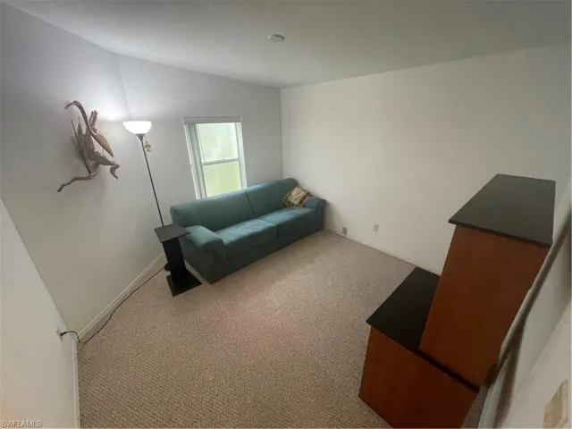 Living area with carpet flooring and vaulted ceiling