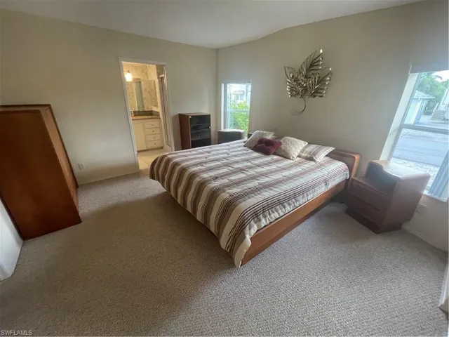 Bedroom featuring light colored carpet and ensuite bathroom