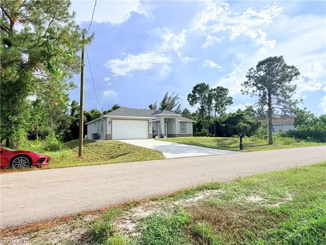 Single-story residence featuring a gray exterior, a white garage door, and a paved driveway