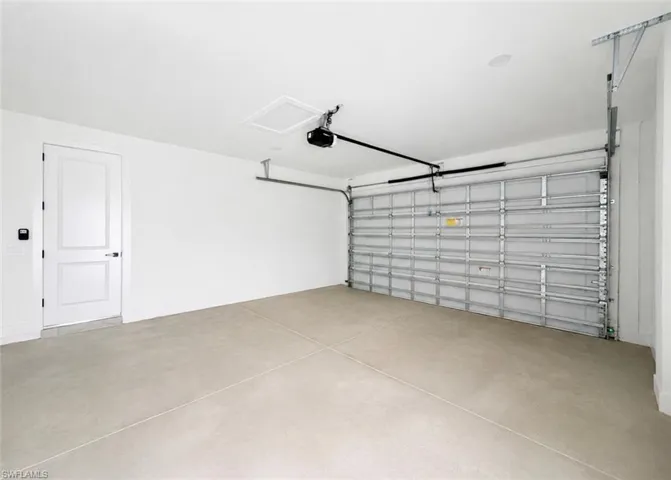 Spacious garage featuring a light-colored concrete floor, white walls, and an overhead garage door