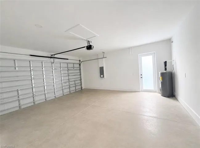 Spacious garage with an automatic door opener, concrete flooring, and a side access door