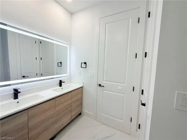 Dual vanity with wood-finish cabinetry, integrated white sinks, and matte black fixtures
