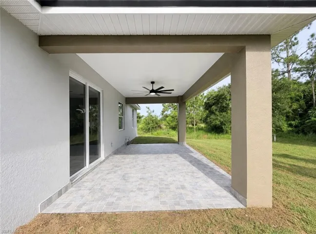Covered patio with tile flooring, ceiling fan, and sliding glass door