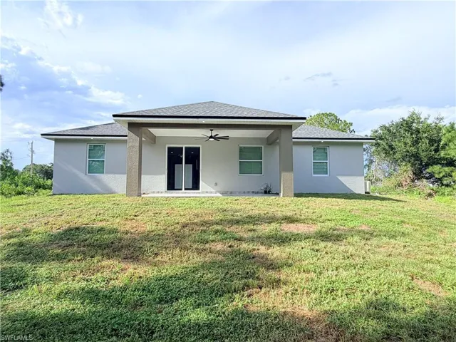 Rear exterior with covered patio, sliding glass doors, exterior ceiling fan, and multiple windows